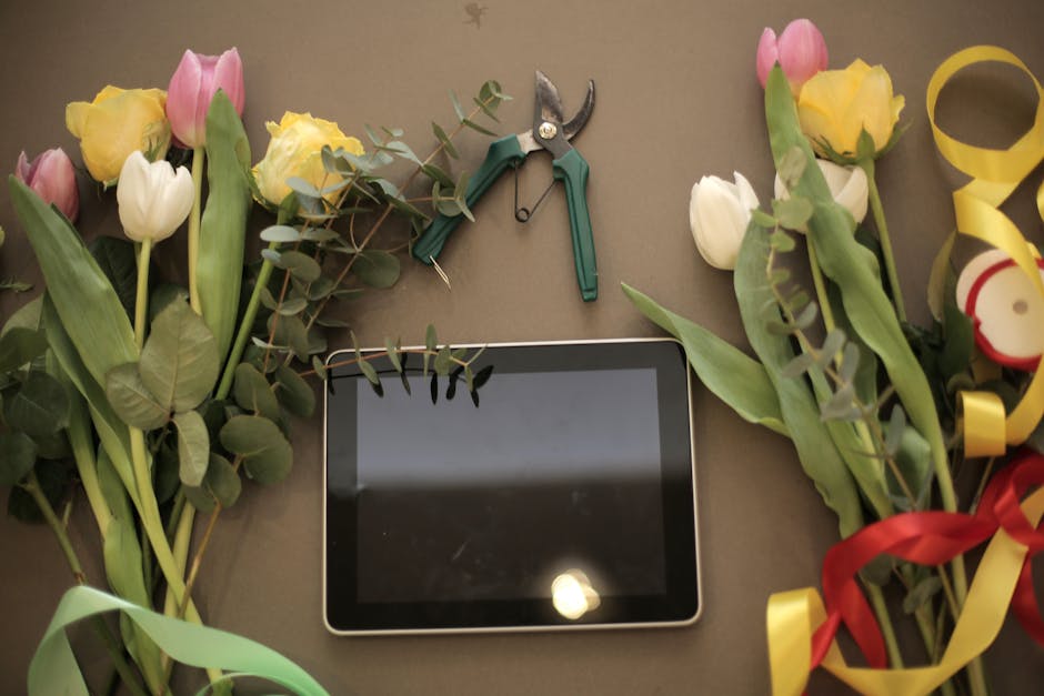A flat lay image featuring multiple bouquets of fresh tulips in shades of pink, yellow, and white, with green leaves and stems, arranged on a neutral surface. Some bouquets are wrapped with colorful r